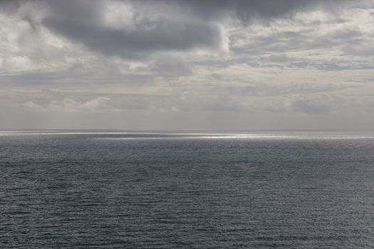 A tranquil seascape with a moody, cloudy sky above a vast ocean, creating a calming natural scene.