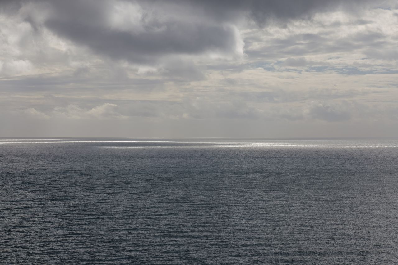a tranquil seascape with a moody cloudy sky above a vast ocean creatin