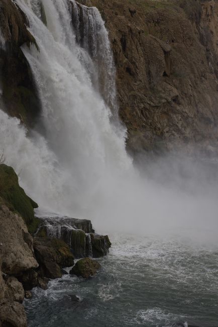 Breathtaking view of a powerful waterfall cascading over rocky cliffs with mist rising.