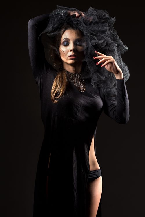Free Studio shot of a woman in a stylish black dress and veil, striking a graceful pose. Stock Photo
