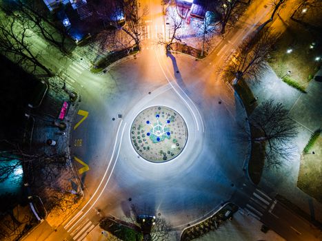 A stunning aerial view of a roundabout at night with vibrant lights and clear roads.
