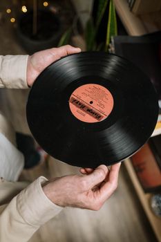 Close-up of hands holding a vintage vinyl record indoors.