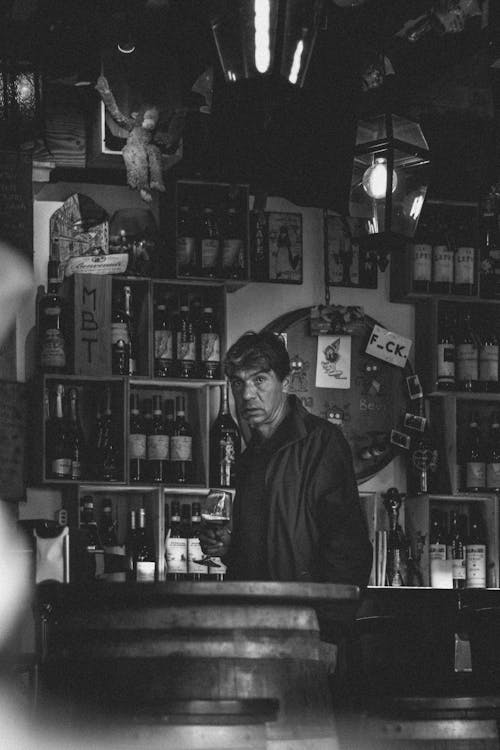 Free Grayscale Photo of Man Standing Behind a Bar Counter Stock Photo