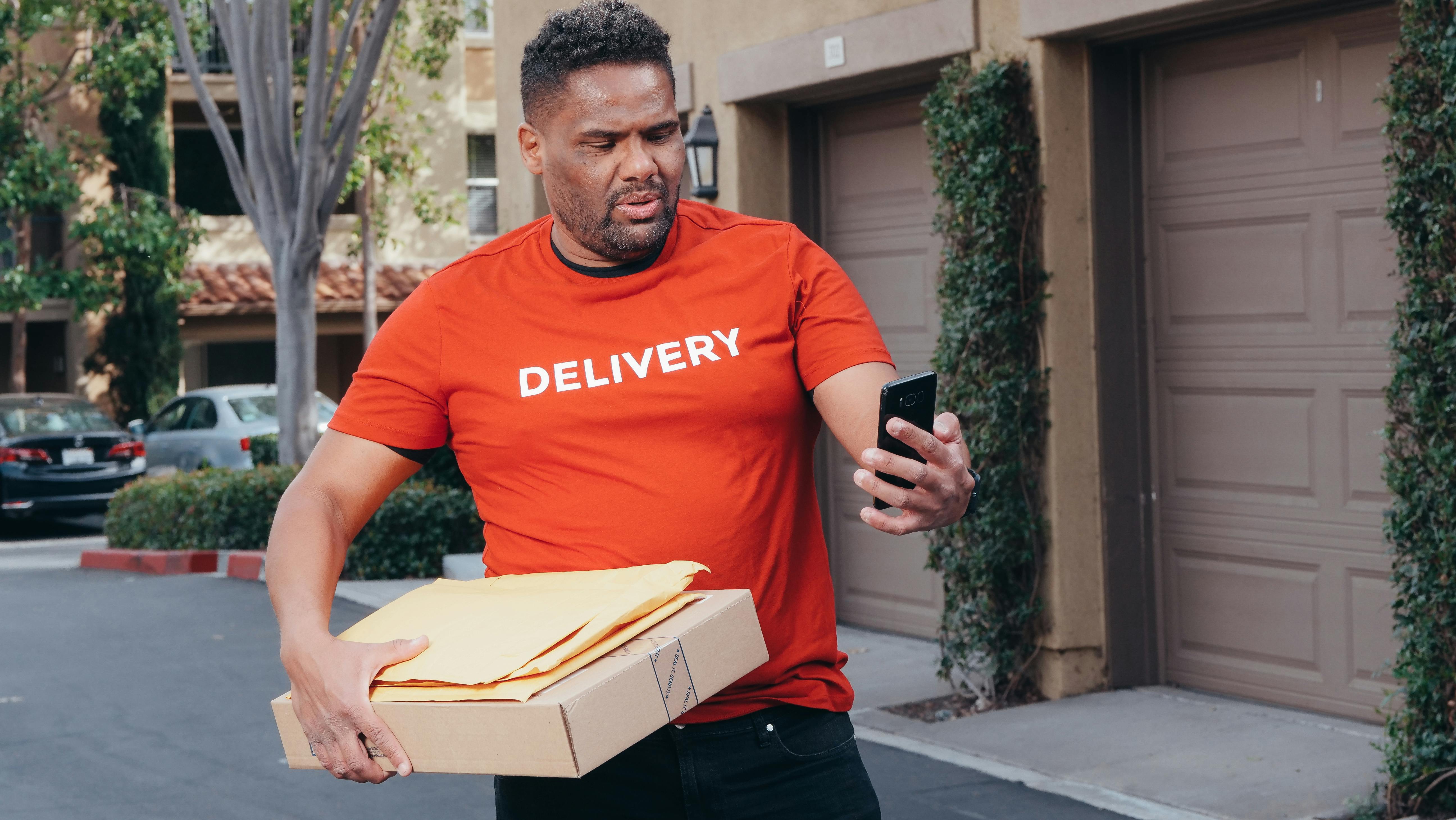 a deliveryman carrying package and mails looking lost and confused