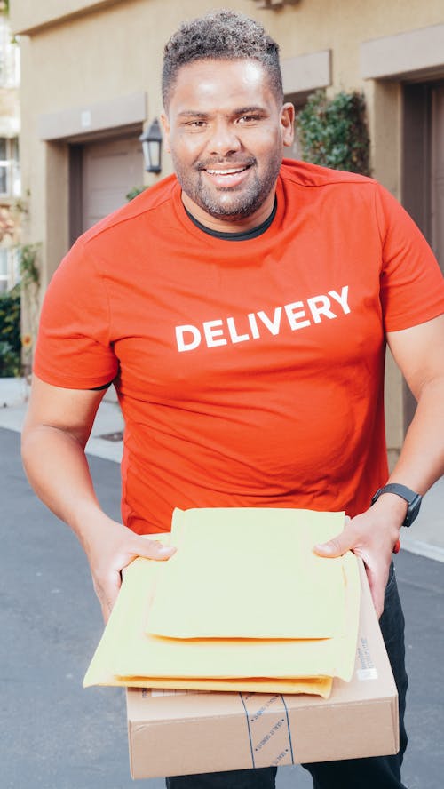 Man in Red Crew Neck T-shirt Carrying a Package and Mails