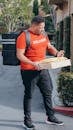 A Deliveryman Carrying a Package and Mails Looking for the Address