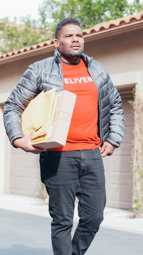 Free Man in Gray Jacket Carrying a Package and Mails For Delivery Stock Photo