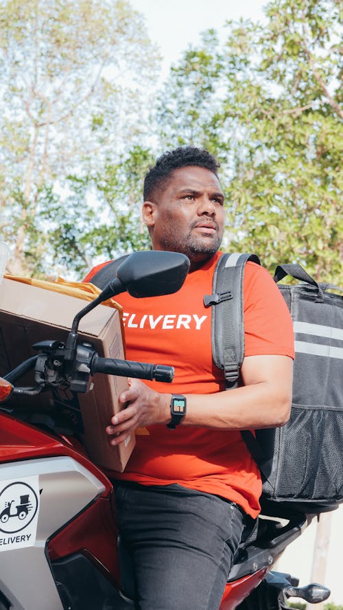 Man in Red T-shirt Riding on a Motorcycle With a Package and Mail For Delivery