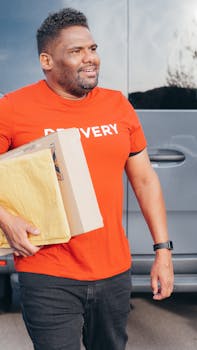 African American courier in a red shirt delivers packages with a smile outdoors. Perfect for delivery service concepts.