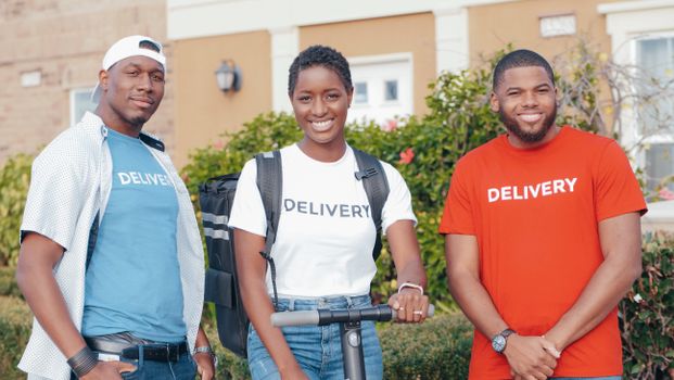 A diverse group of delivery workers smiling outdoors, showcasing teamwork and professionalism.