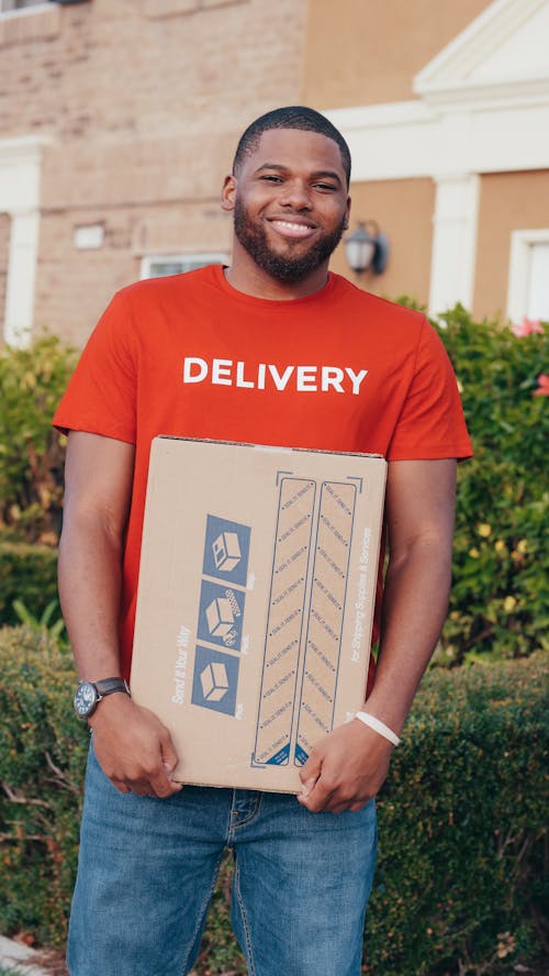 A Man in Orange Shirt Holding a Carton Box