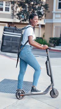 Smiling courier riding an electric scooter while delivering packages in a residential area.