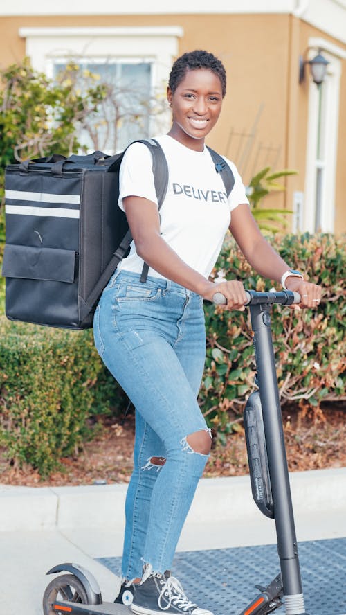 Woman in White and Black Crew Neck T-shirt and Blue Denim Jeans Riding Bicycle during