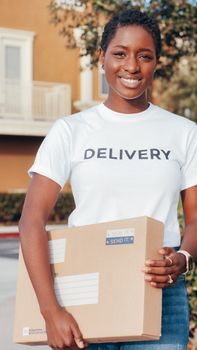 African American female courier with a parcel, delivering a package outdoors, smiling.