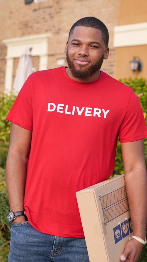 Man in Red Crew Neck T-shirt Carrying a Parcel