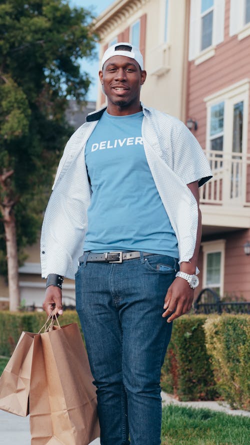 Man in Blue Crew Neck Shirt Carrying Paper Bags