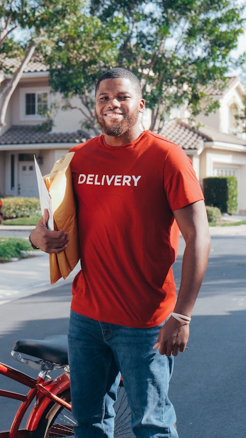 Man in Red Crew Neck T-shirt Holding Brown Paper Bags