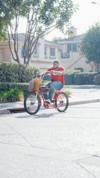 Courier on a red bicycle delivering packages in a sunny suburban neighborhood.
