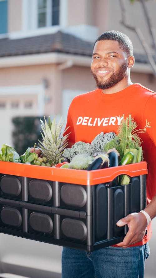 Man in Red Crew Neck T-shirt Holding a Crate of Fresh Vegetable