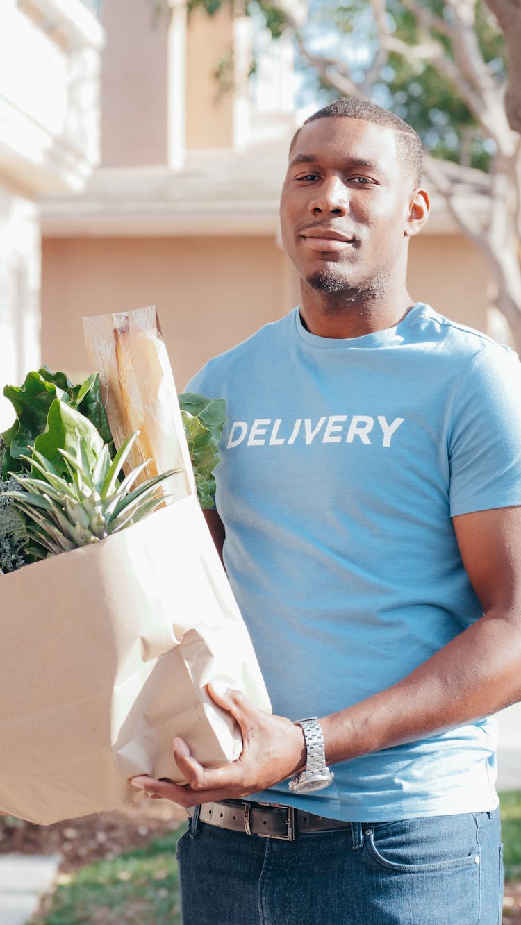 A Delivery Man Carrying A Bag Of Grocery