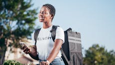 Woman in White Crew Neck T-shirt Carrying Black Delivery Bag
