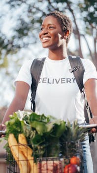 Young delivery woman smiling while delivering fresh fruits and vegetables outdoors.