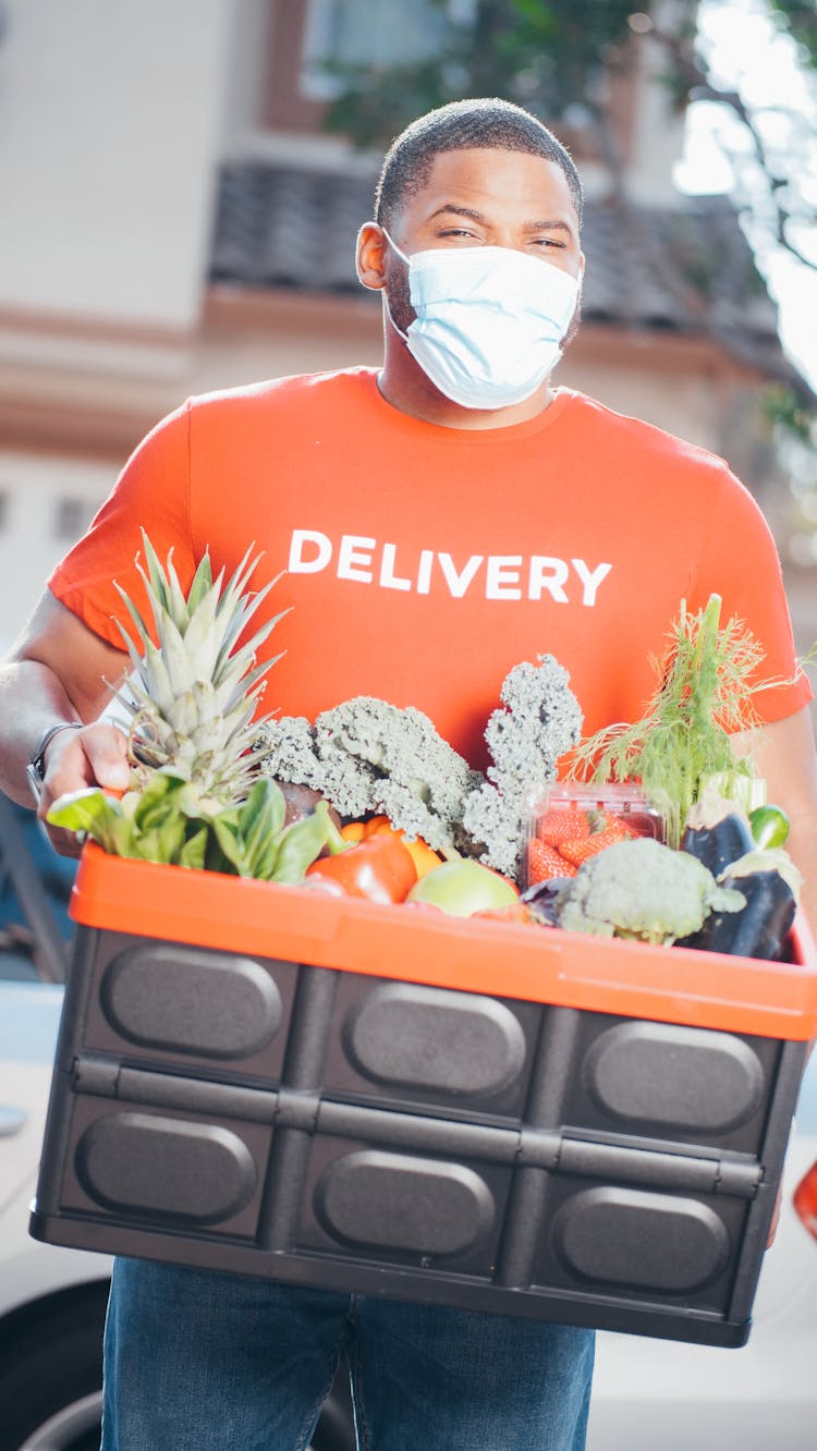 A Delivery Man Carrying A Box Of Grocery