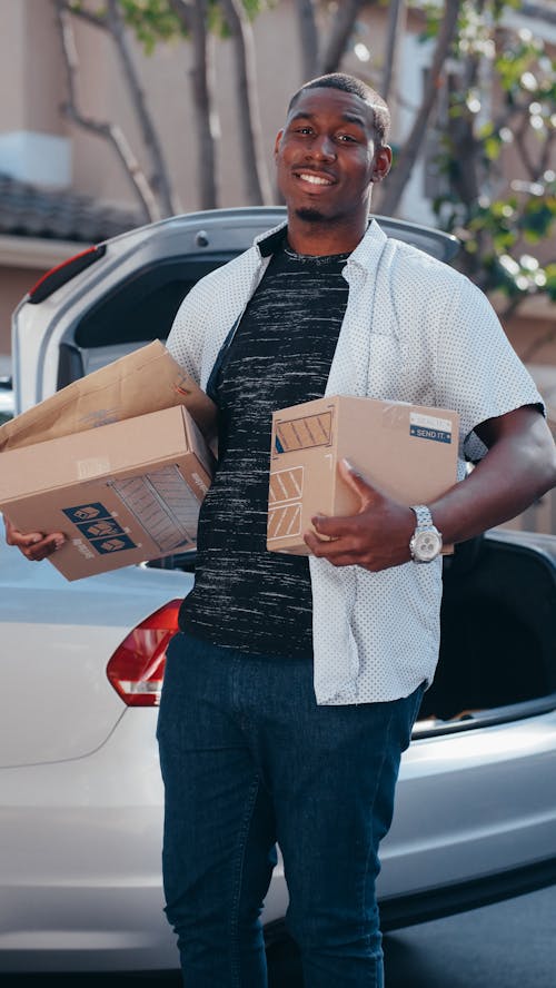 Free A Man in White Button Up T-shirt Holding Brown Cardboard Boxes Stock Photo