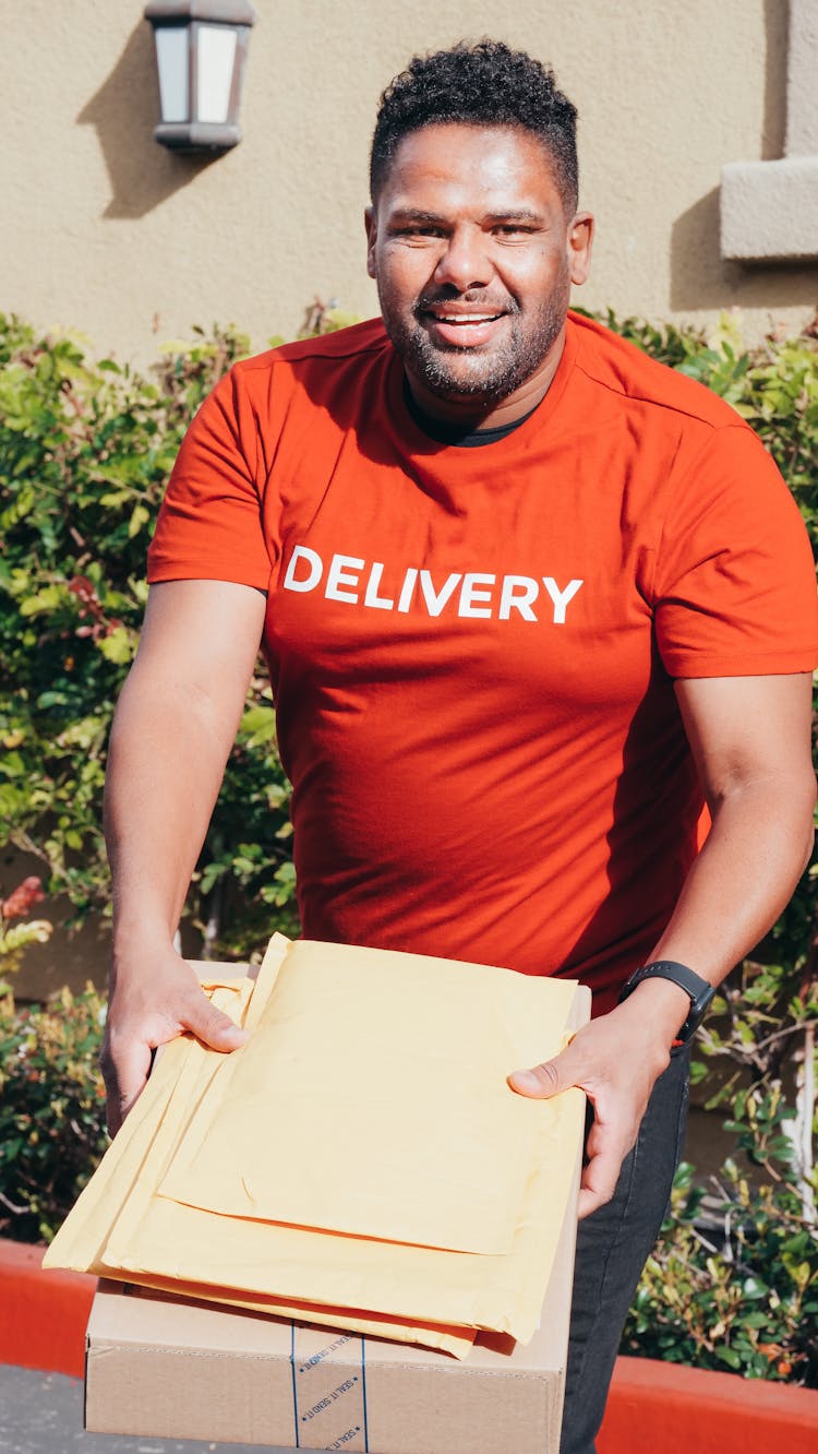 A Man In Red Shirt Holding Brown Envelopes