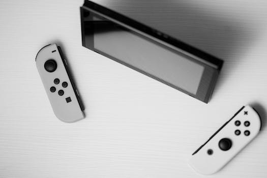 Black and white minimalist flat lay of Nintendo Switch console with game controllers on a white surface.
