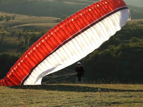 Man on the Ground With a Red Black and White Parachute