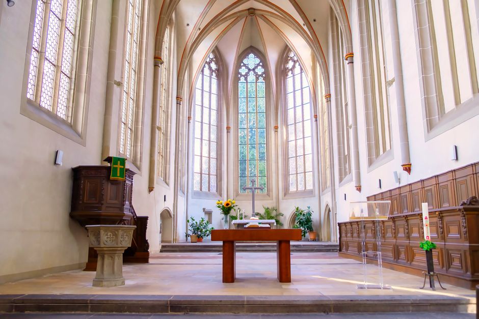 Cathedral interior with a vaulted ceiling, altar, and stained glass windows