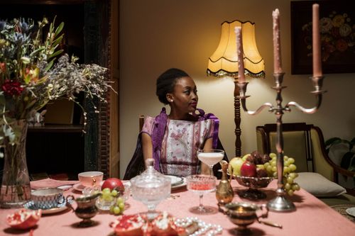 Free Elegant indoor dining setting with a woman in stylish attire. Beautiful decor with candles and fruits. Stock Photo