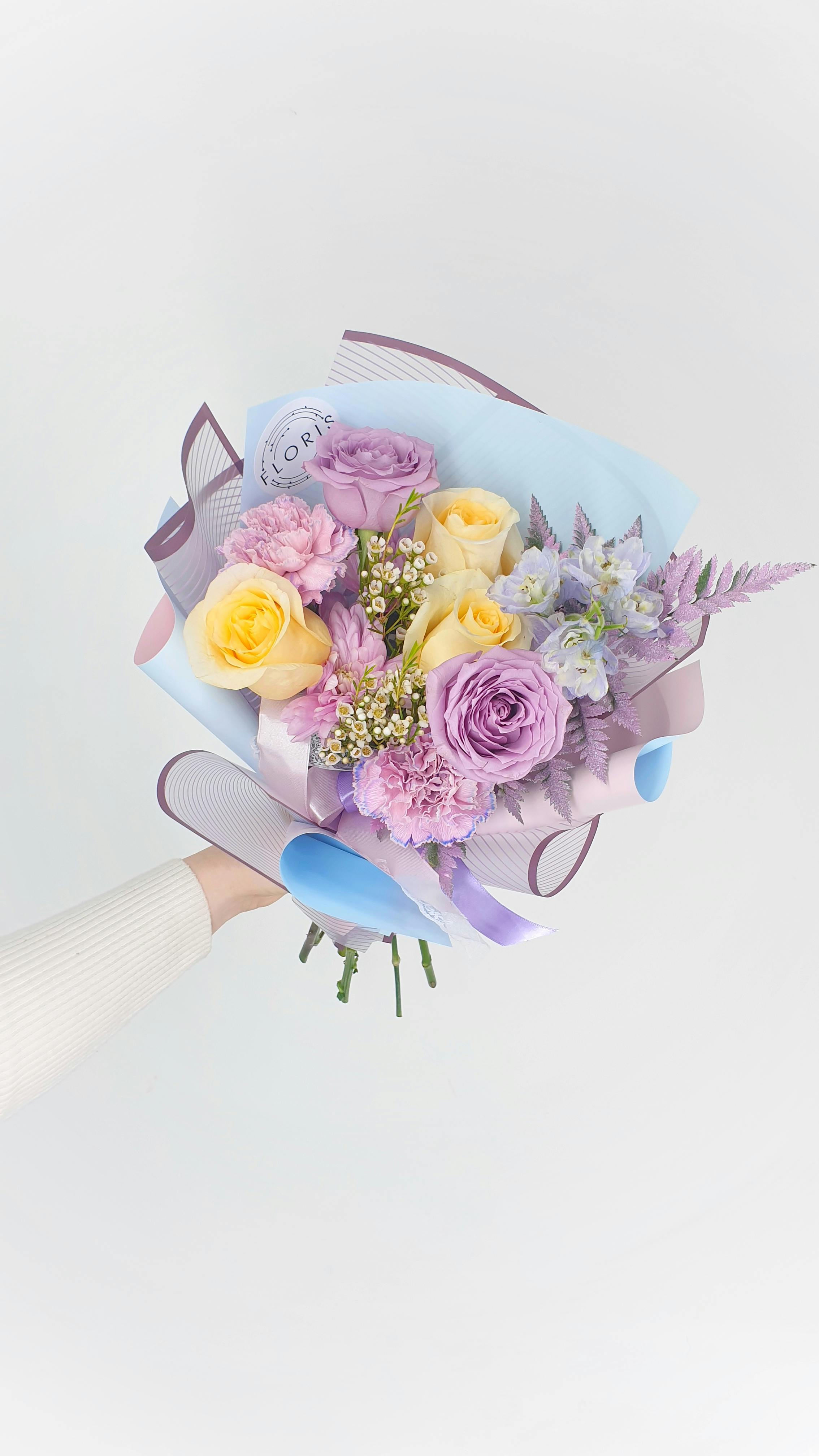 woman showing bouquet of flowers wrapped in paper