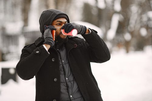 Free A man in winter clothes talking on the phone and enjoying a hot drink outdoors. Stock Photo