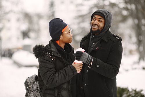 Free A couple in winter clothing enjoying hot drinks outdoors on a snowy day. Stock Photo