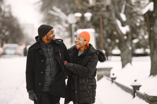 Free Smiling couple walking through a snowy park, enjoying winter together. Stock Photo