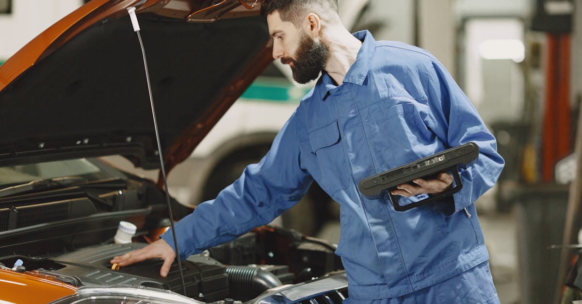 Professional mechanic examining a car engine under an open hood in a garage setting.