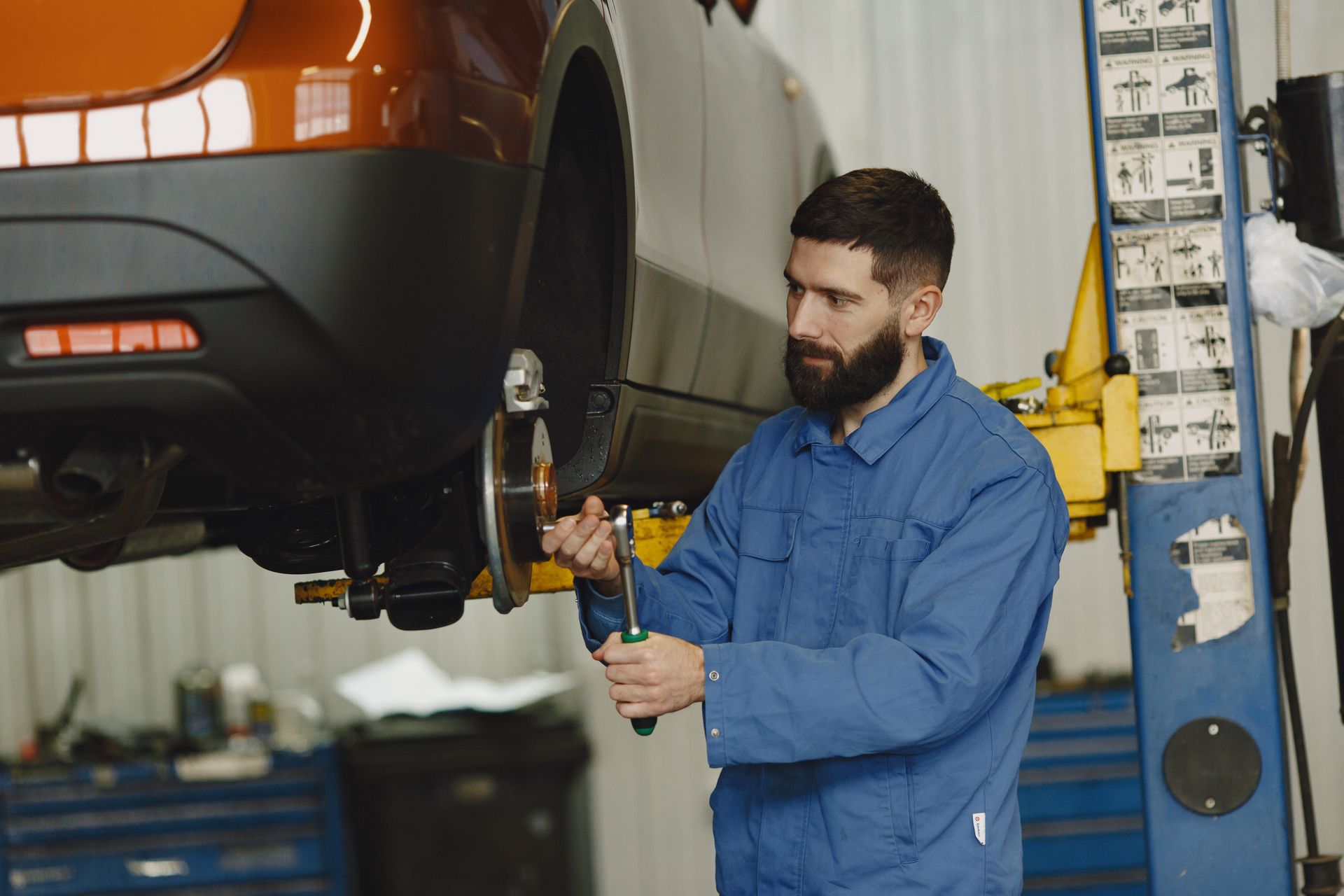Professional mechanic working on car maintenance in an automotive garage.