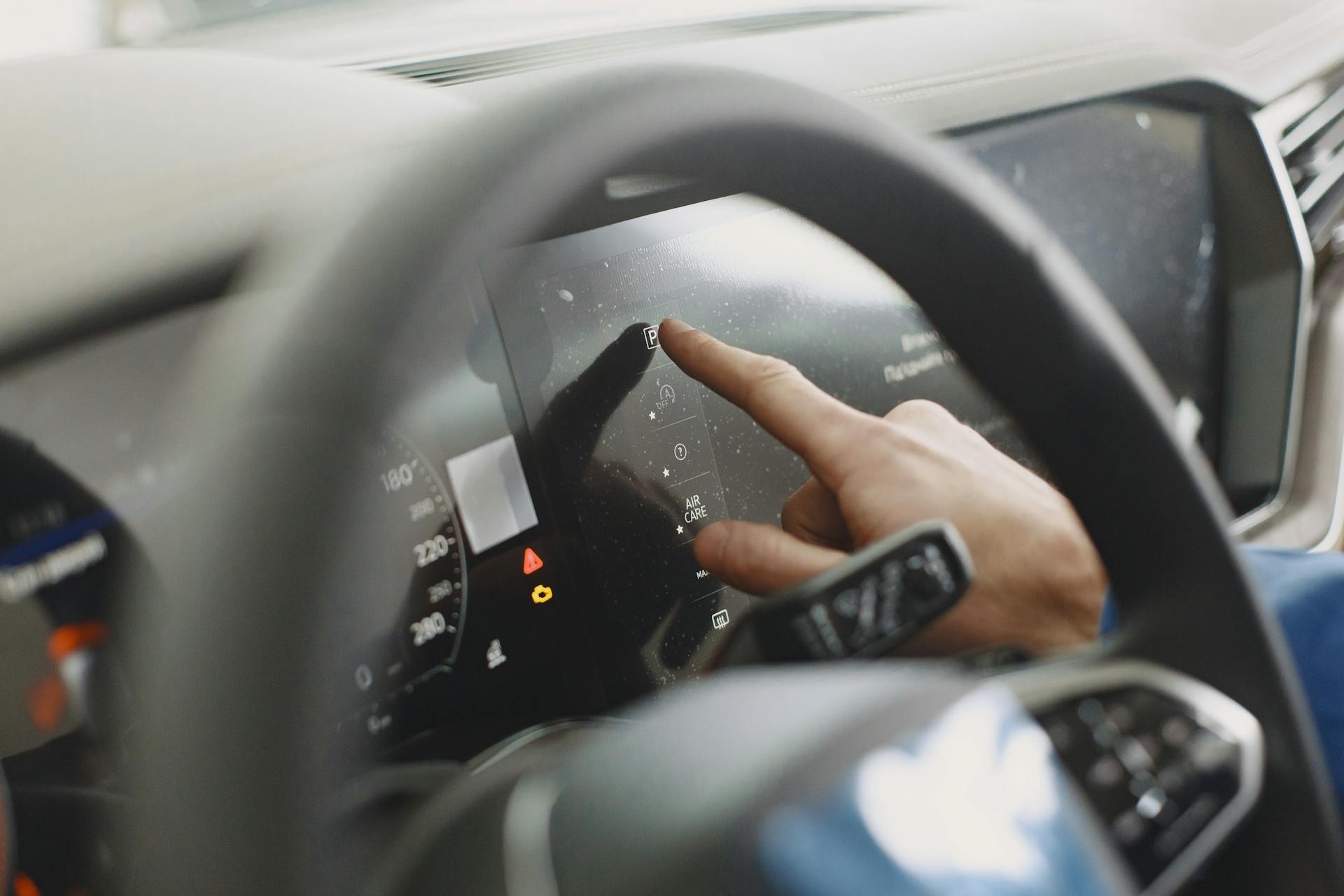 Close-up of a hand interacting with a car's digital dashboard. Modern technology and driving interface.