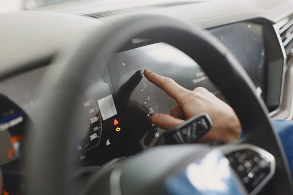 Hand interacting with digital car dashboard for predictive maintenance data