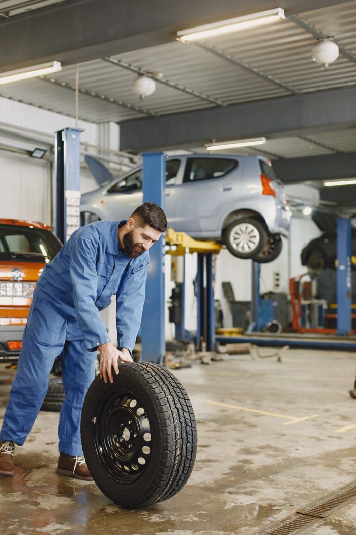 Mechanic handling a tyre in a busy automotive workshop