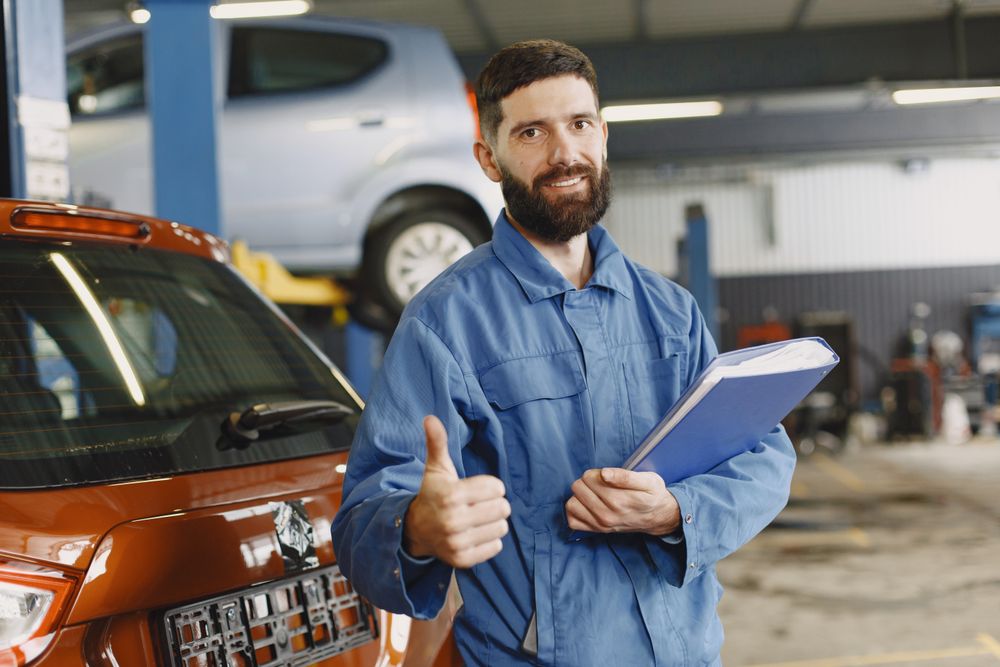 Mechaniker in blauer Arbeitskleidung mit Klemmbrett in der Werkstatt