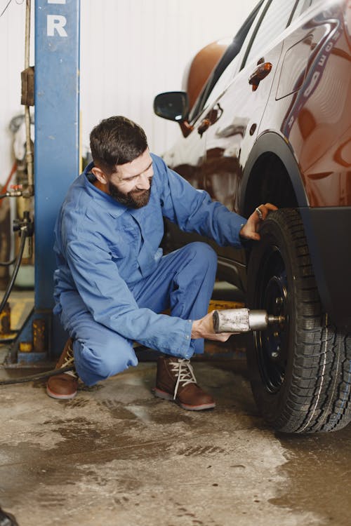 Man in Blue Dress Shirt and Blue Denim Jeans Sitting on Brown Wooden Seat