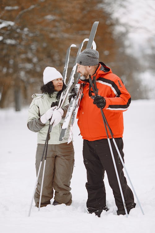 Couple Standing on Snow Covered Ground Holding Ski Poles