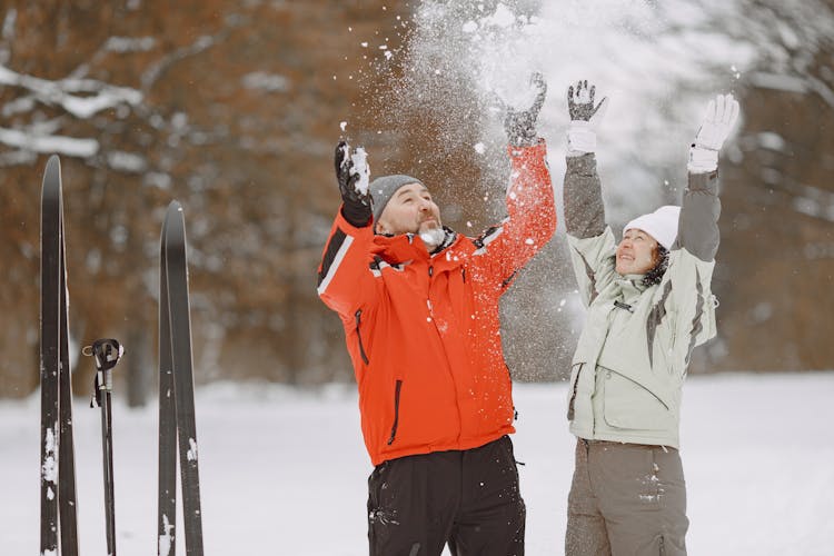 Man And Woman Throwing Snow In The Air