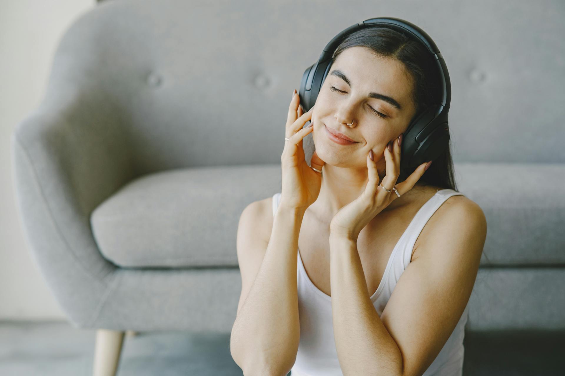 Serene woman relaxing with wireless headphones, eyes closed, enjoying music at home.