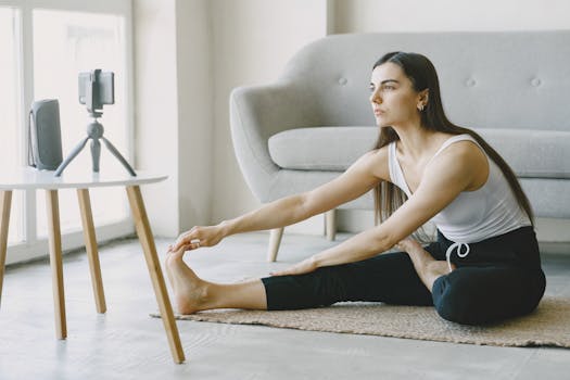 Adult woman doing seated stretches indoors, recorded by camera. Ideal for fitness and wellness content.