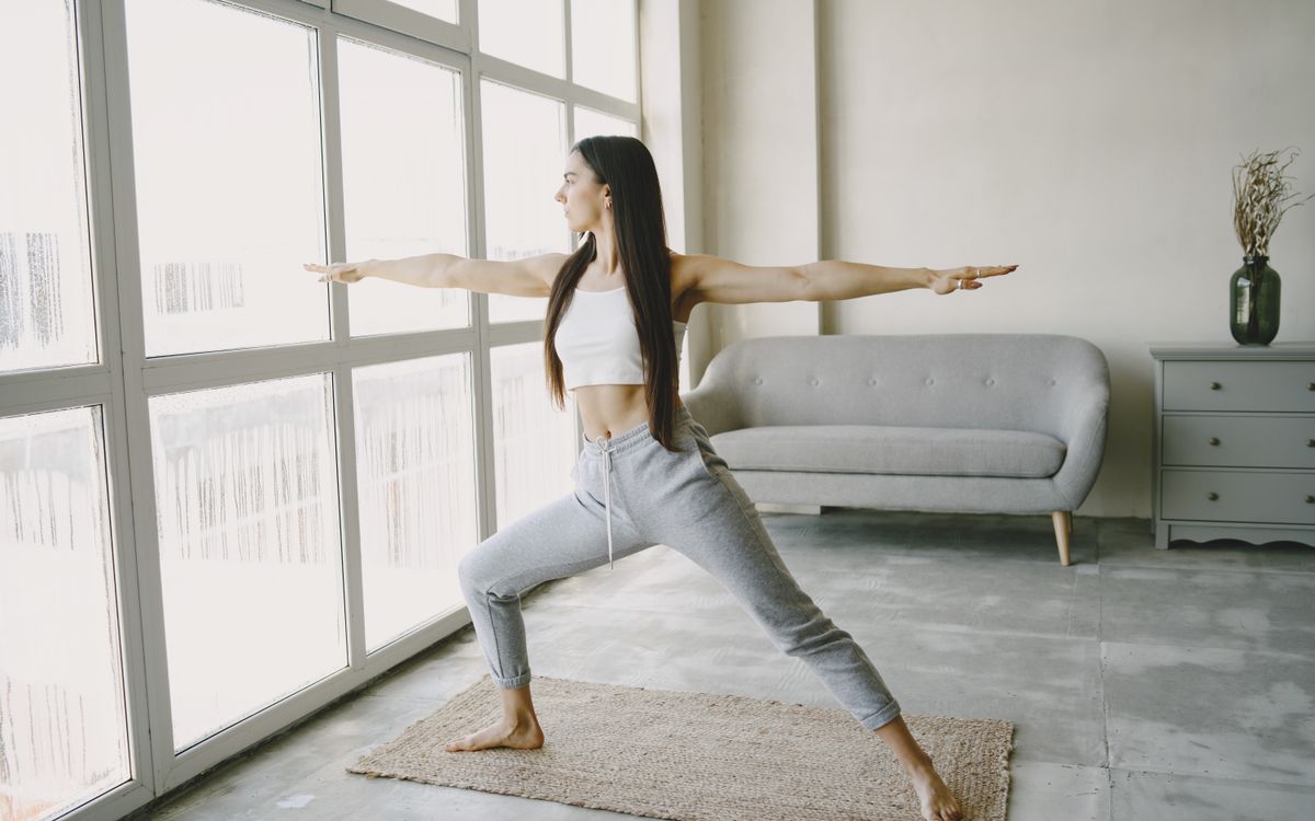 Woman practicing yoga poses in a bright living room, promoting relaxation and wellness.