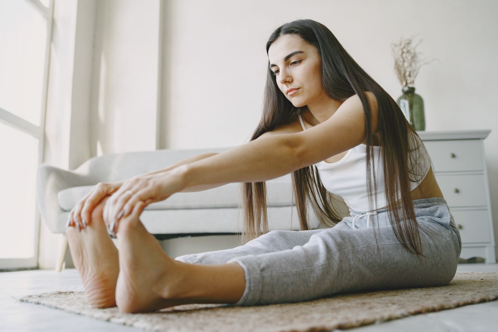 Woman stretching in a sunlit room as part of a calming morning routine for wellness